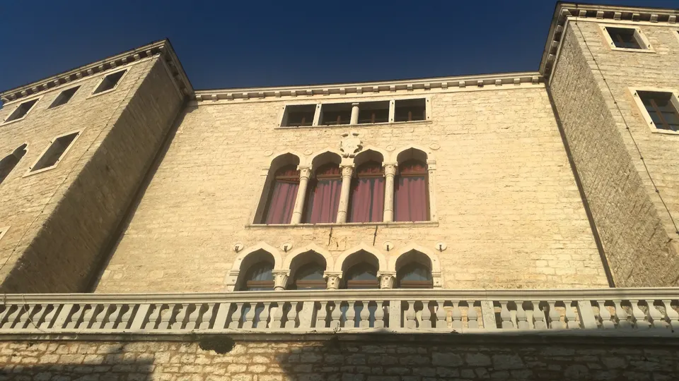 Gothic windows and a long stone balcony on the Soardo-Bembo castle in Bale.