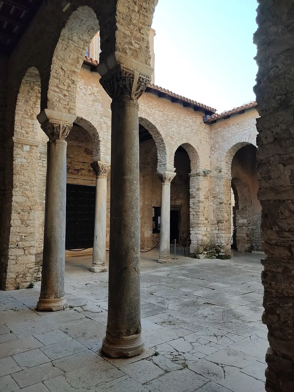 The arcaded stone atrium of the Euphrasian Basilica in Poreč, with columns and carved capitals.