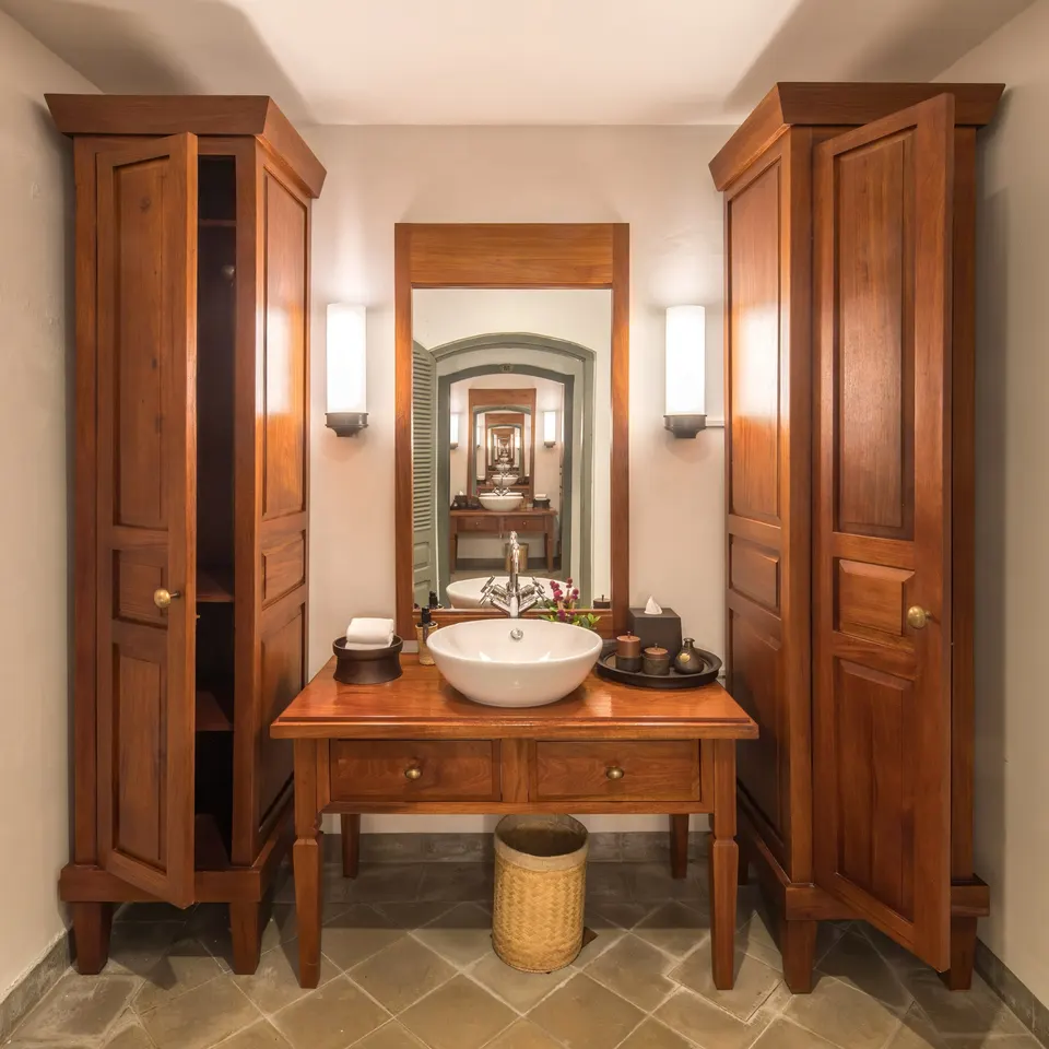 Tall wooden cabinets either side of a vanity: closed storage keeps towels, linen and spare toiletries dry.