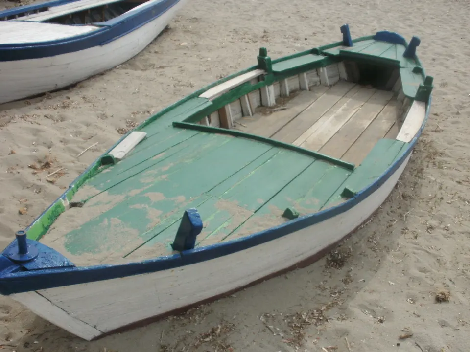 A batana, the traditional flat-bottomed wooden boat of the Istrian coast, pulled up on the sand.