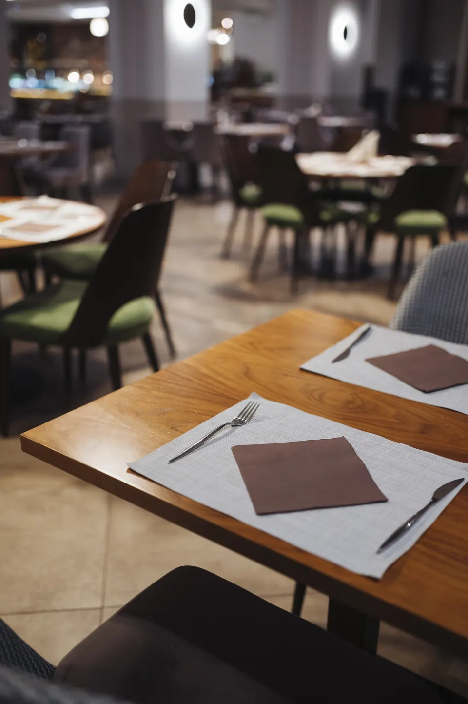 Tables and chairs in a restaurant dining room, set and waiting for the evening's guests.
