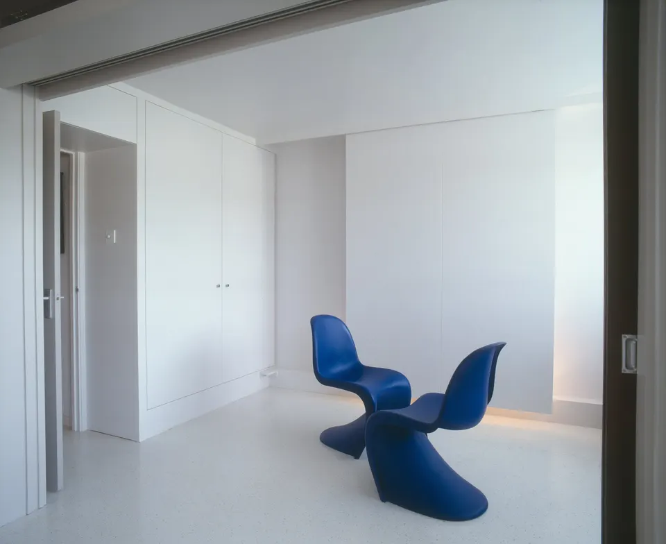 A wall of full-height built-in cupboards keeps a small studio clear and calm.