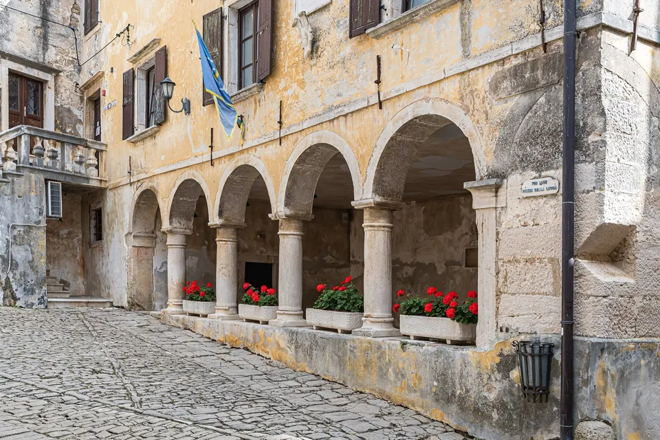 The arcaded loggia of Grožnjan, with red geraniums between the columns.