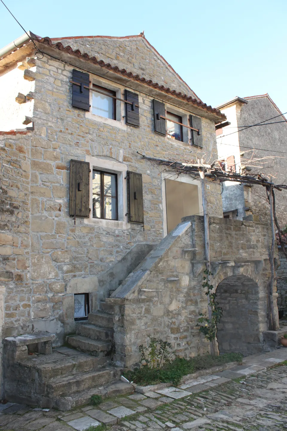 A traditional Istrian stone house with an external stair and terrace, the baladur, and wooden shutters.