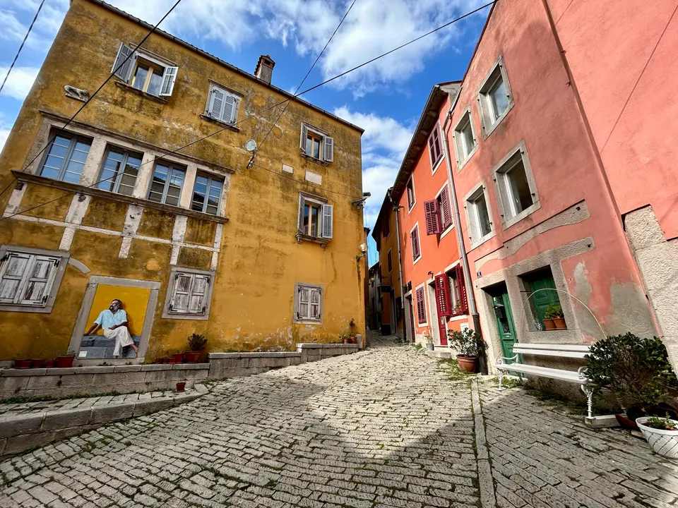 Old Square (Stari trg) in Labin's old town, with ochre and pink facades and a cobbled street.