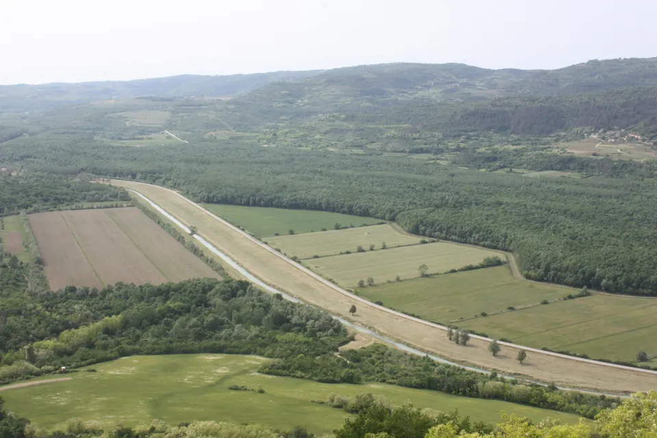 The Mirna valley seen from Motovun, with fields and the river forest below.