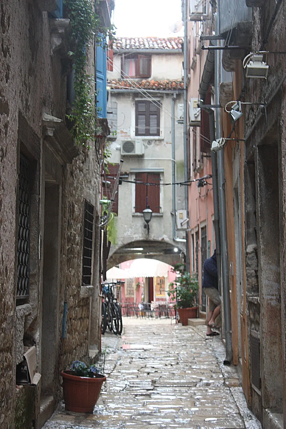 A stone-paved lane in Rovinj's old town, with an arch leading to a small square.