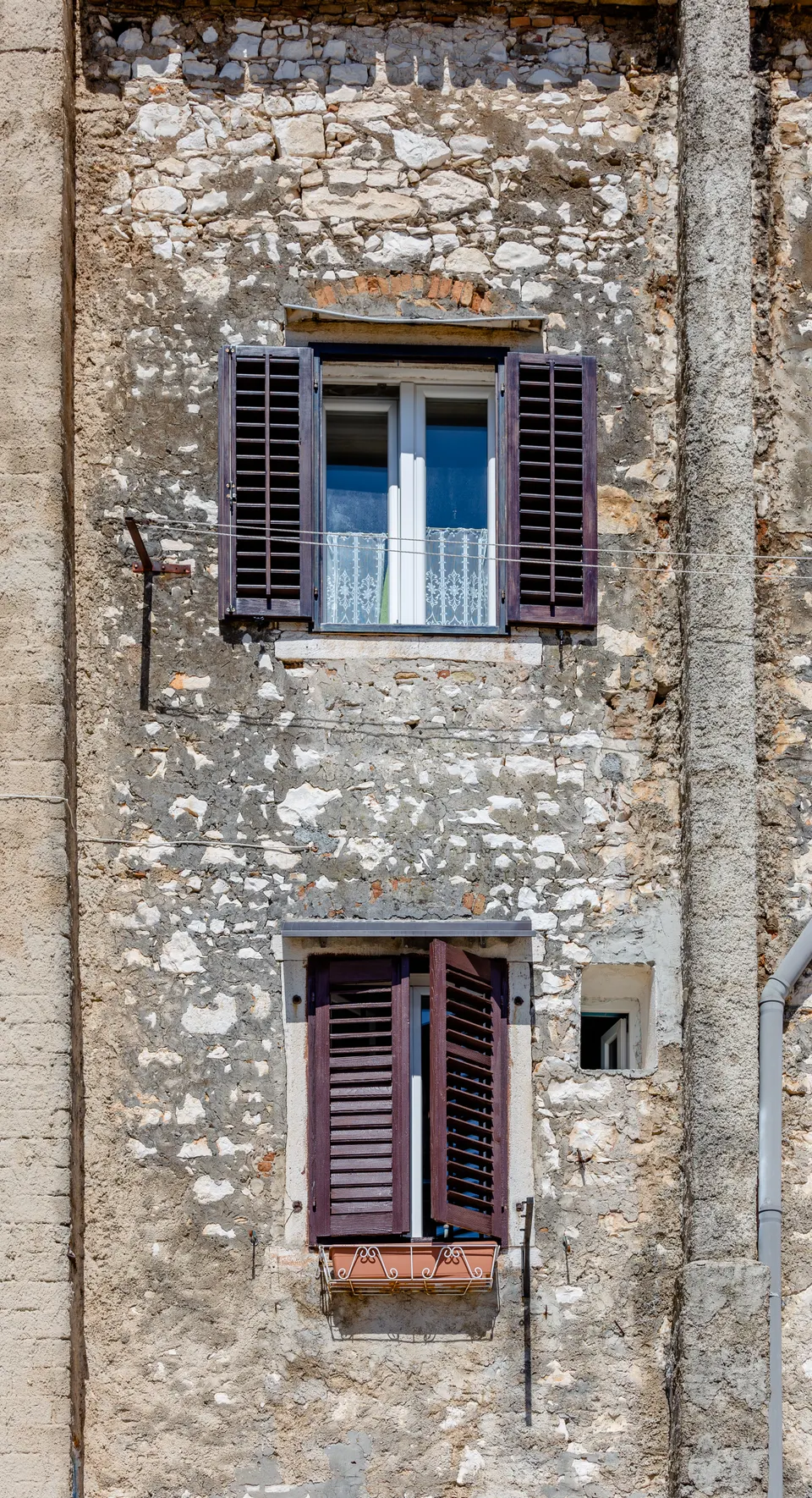 Windows with louvred shutters on an old stone house on the coast in Umag.