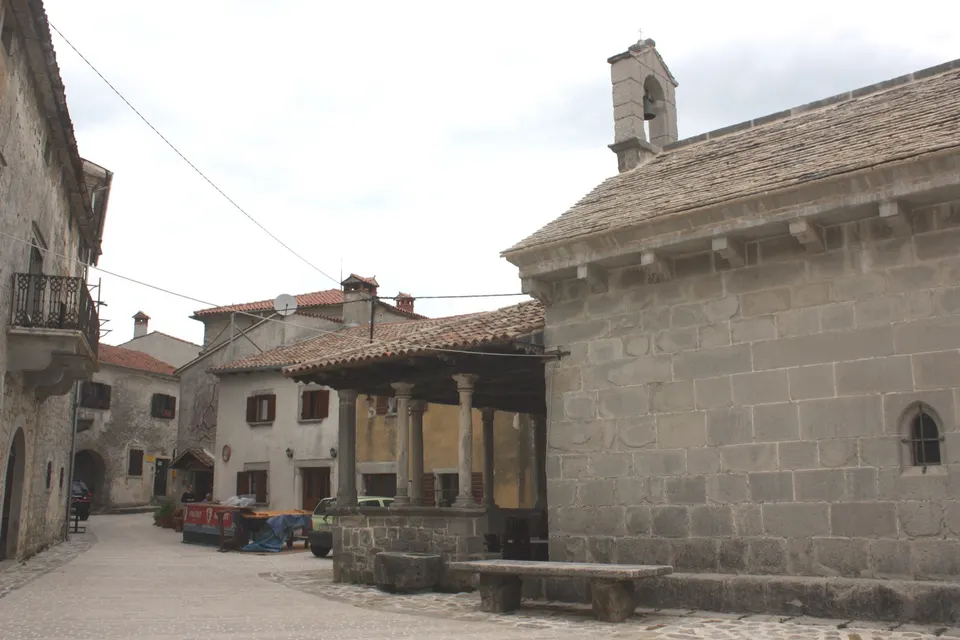 La chiesa in pietra di Santa Maria a Gračišće, con accanto la loggia a colonne sulla piazza del borgo.