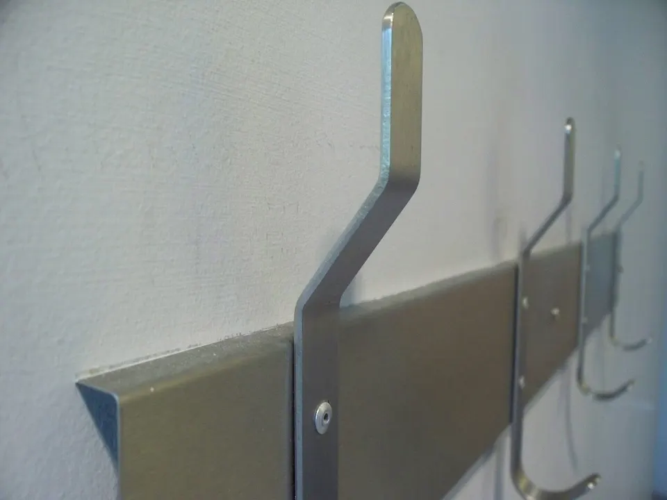 Una fila di semplici ganci in acciaio spazzolato fissati a una parete bianca: i pochi centimetri più utili di qualsiasi ingresso.