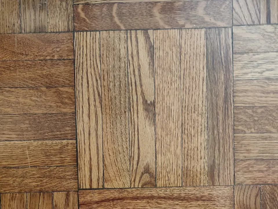 Close-up of an oak parquet floor laid in square panels, with the grain of each block running in a different direction.