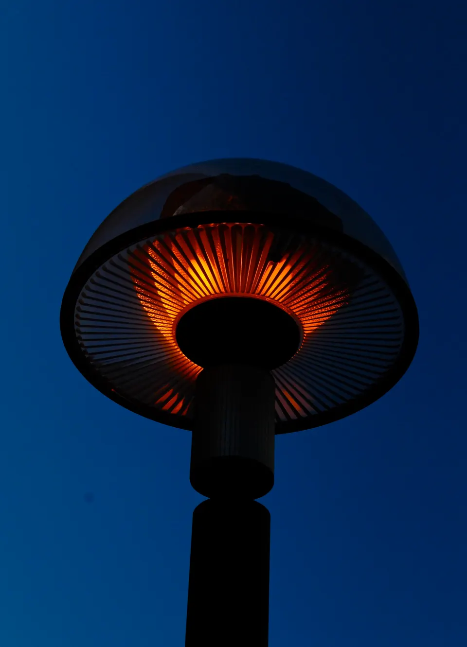A mushroom-style outdoor heater glowing against the evening sky: the kind of heat that lets guests stay on the terrace on cool spring and autumn nights.