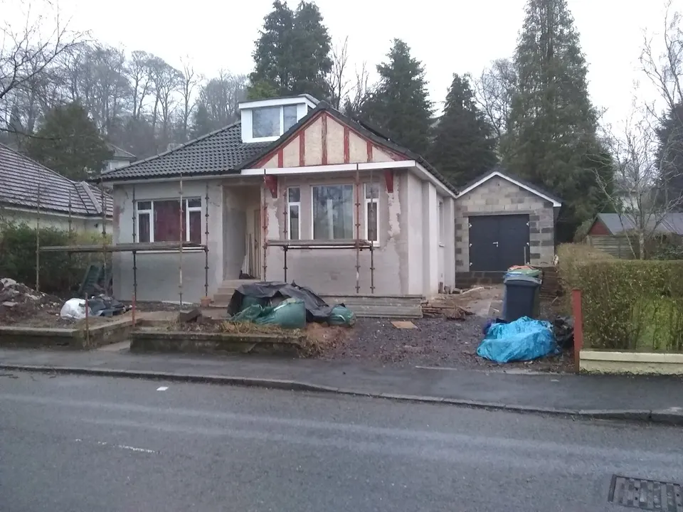 A house mid-renovation, with scaffolding along the front, new render and building waste in the garden. Each of these things is a line on a quote, or a gap in one.
