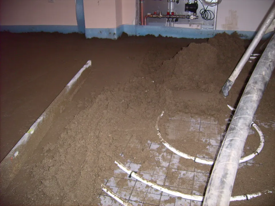 Screed being spread over underfloor heating pipes. Thickness, type and drying time all change the price of the same line item.