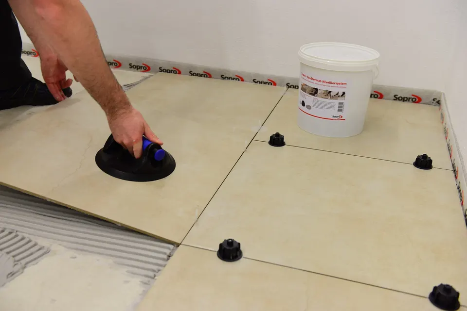 Großformatige Bodenfliesen werden mit einem Saugheber und Nivellierclips verlegt. Unter keramičarski radovi sollte im Angebot stehen, welche Fliesen, welches Format und welche Verlegeart.