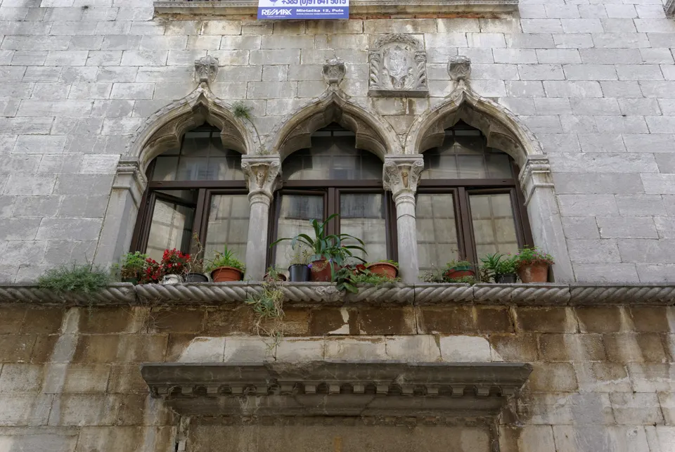 Venetian Gothic windows and a stone balcony on a house along the Decumanus in Poreč.