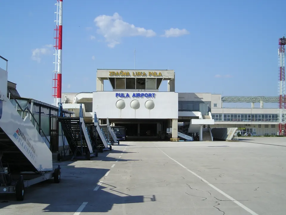 The terminal of Pula Airport seen from the apron, with boarding stairs lined up in the foreground.
