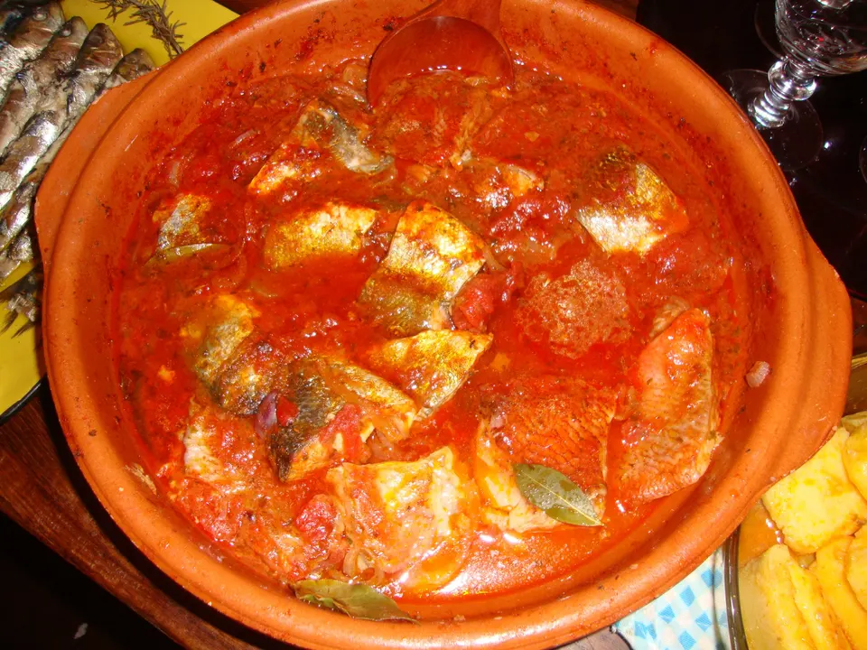Brodet in a terracotta dish: pieces of fish in a rich tomato sauce, with slices of polenta on the side.