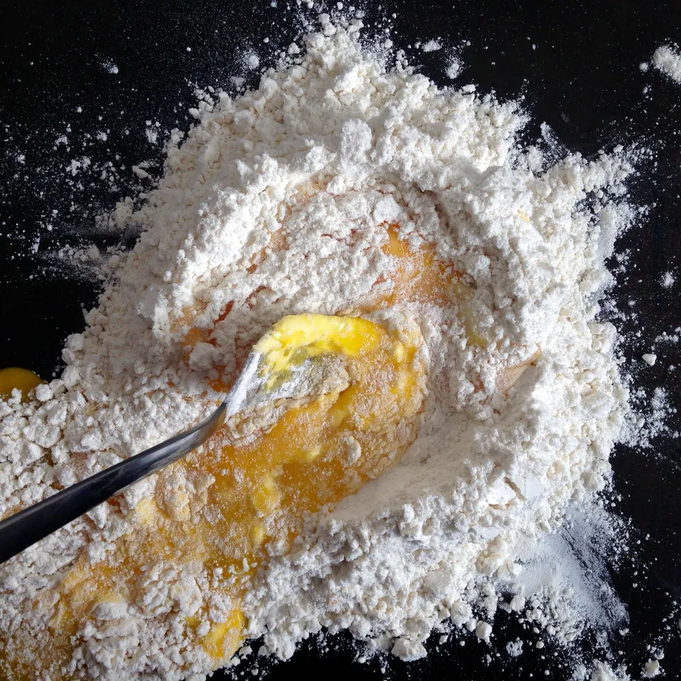 Eggs being worked into a well of flour with a fork: the first step of any fresh egg pasta.
