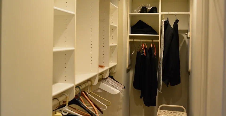 Inside a walk-in closet: adjustable shelves, short and long hanging rails and a shelf for shoes.