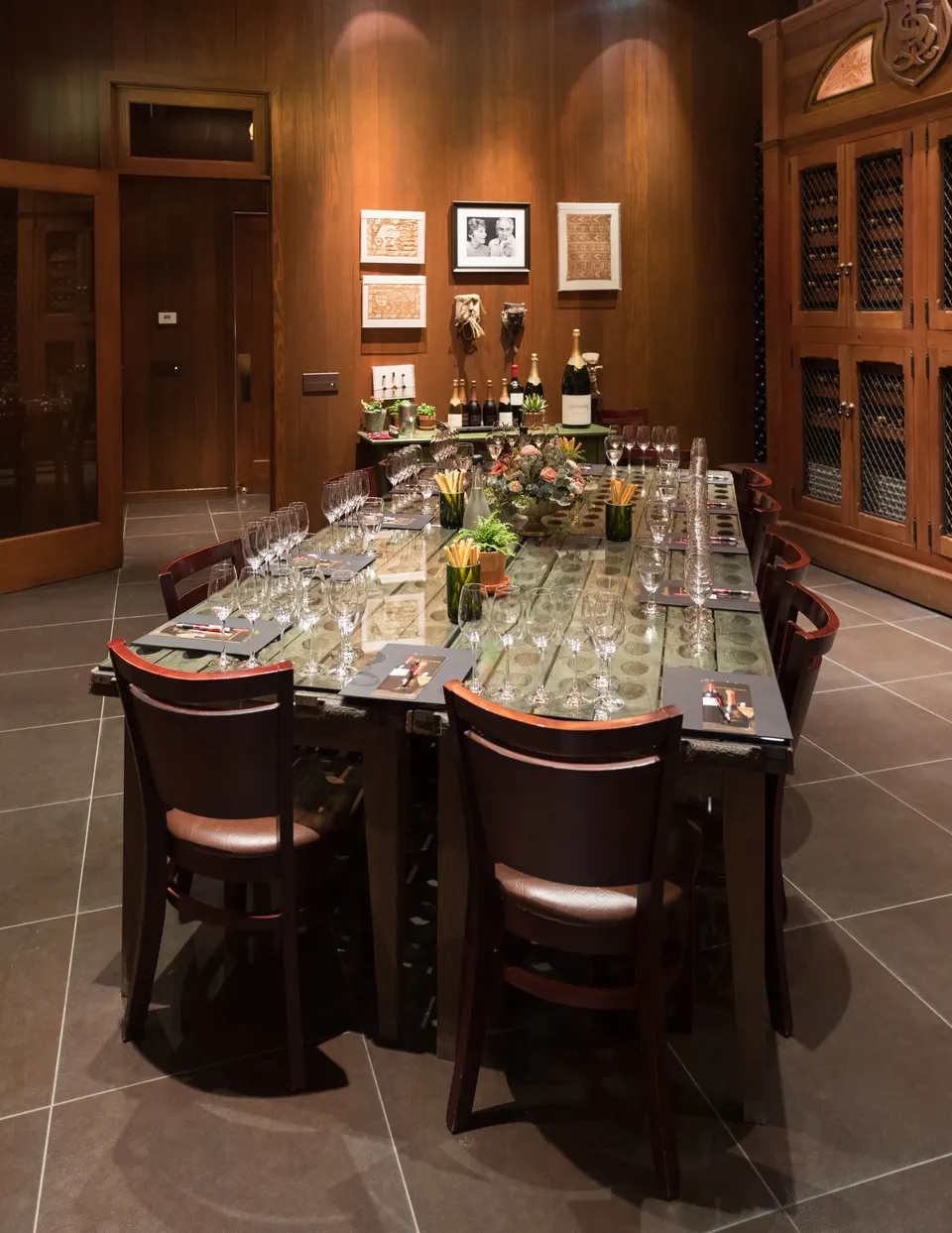 A winery tasting room with wood-panelled walls and a long table set with rows of wine glasses.